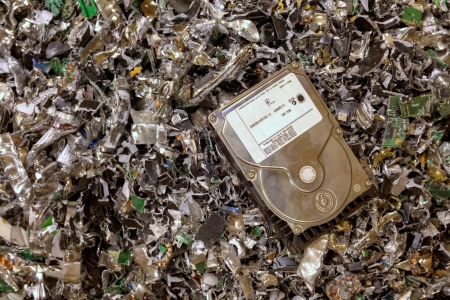 A hard drive resting on a pile of shredded hard drives