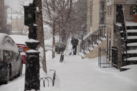 Man shoveling in front of its house during a snow storm in Washington DC