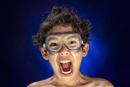 A crazy child with lab glasses,  screaming funny, on blue backgroundの写真素材