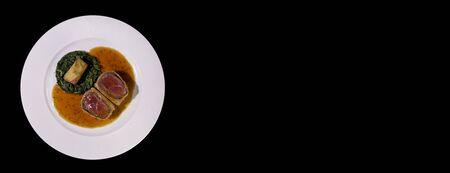 Beef Wellington with Spinach and fried potatoes.Isolated on a black background.Panorama for banners.Copy spase.の写真素材