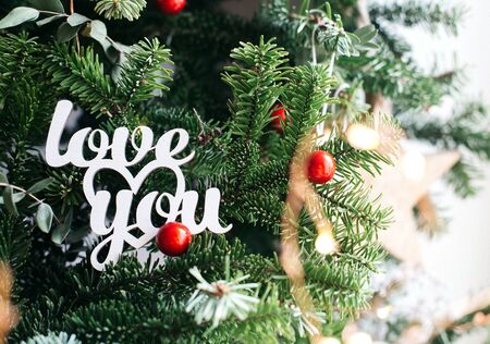 Love you inscription on green fir background. White wooden phrase for valentine's day. Christmas decoration.の写真素材