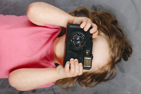 Little girl photographer with camera smiling and take a picture. Top view.