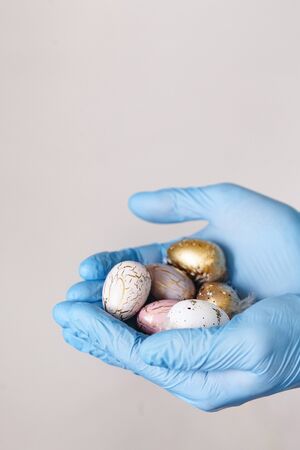 Hands in medical gloves holding modern painted easter eggs. Selective focus. Toned picture....