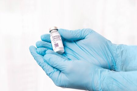 Coronavirus vaccine. Doctor with a vaccine. Hands holding a coronavirus vaccine ampoule, against...