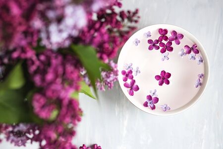 Five-pointed lilac flower among lilac flowers in a cup with water. Spa ritual. Lilac branch with a flower with 5 petals.の写真素材