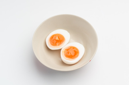 isolated two halves of a boiled egg in a bowl in white backgroundの写真素材