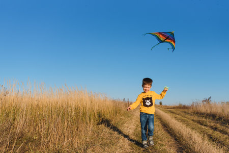 Little boy with kite flying over his headの写真素材