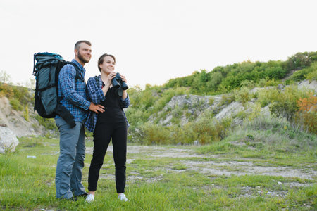 A couple of tourists in time of trip steel and admire the beautiful mountain scenery. The guy hugs the girl. The concept of love, tenderness and recreationの写真素材
