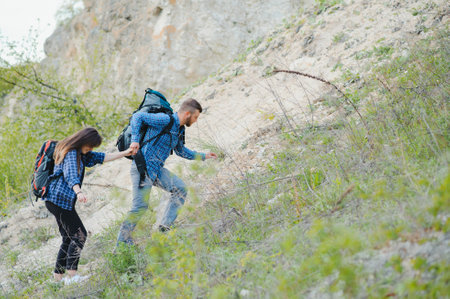 Hiker guy gives a hand to the girl while walking in the mountains, help and friendship concept