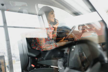Beautiful young mixed race black African American woman driving car and speaks by phone