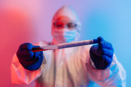 Test tube with blood sample. Scientist with biohazard protection cloth and glove for protectionの写真素材