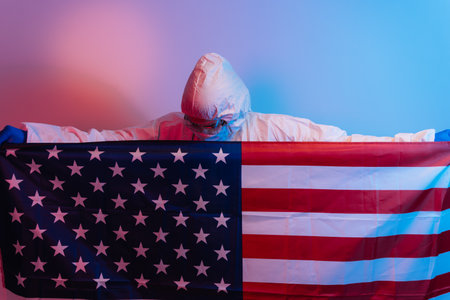 Save the United States from the coronavirus pandemic. Doctor in COVID-19 protective suit, mask and gloves with USA flag. Quarantine concept.の写真素材