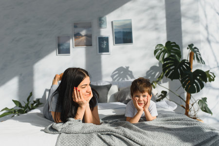 Portrait of a happy mother and her children son lying on a bedの写真素材