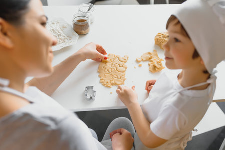 Happy mother and child in kitchen preparing cookiesの写真素材