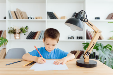 education, childhood, people, homework and school concept - smiling student boy with book writing to notebook at homeの写真素材