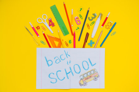 School notebook and stationery over yellow desk. Back to school abstract background. school equipment. Variety of school supplies. flat lay.の写真素材