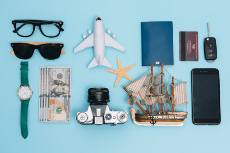 top view travel concept with retro camera films, smartphone, map, passport, compass and Outfit of traveler on blue background with copy space, Tourist essentials, vintage tone effectの写真素材