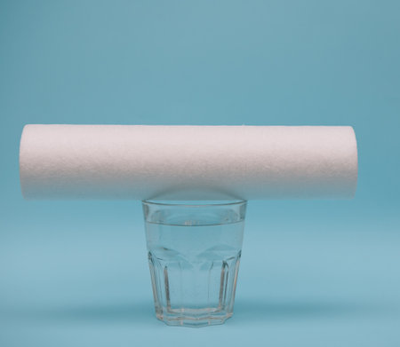 water filters. Carbon cartridges and a glass on a blue background. household filtration systemの写真素材