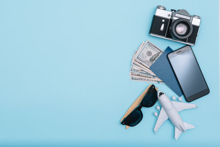 Preparation for Traveling concept, watch, airplane, money, passport, pencils, book, Photo frame, eyeglass on blue background with copy spaceの写真素材
