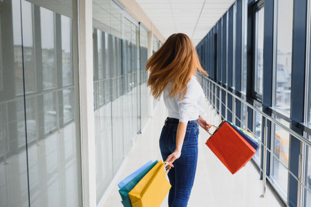Beautiful young woman with bags in shopping centerの写真素材
