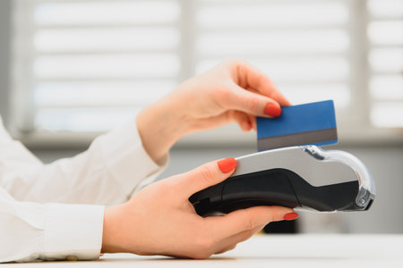 Close up of hand using credit card swiping machine to pay. Hand with creditcard swipe through...