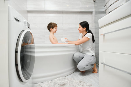 mother washing little son in bathroomの写真素材