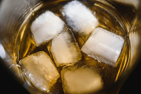 Glass of scotch whiskey and ice over black backgroundの写真素材