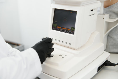 Modern medical equipment. Close up of ophthalmologist using auto refractometer while examining child...