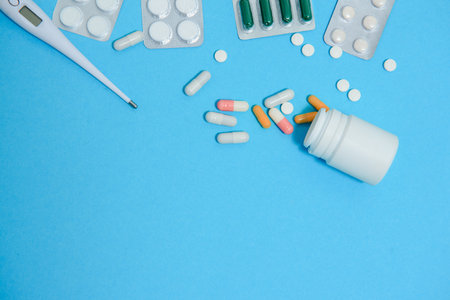 Scattered white pills on blue table.Medical, pharmacy and healthcare concept. Blue background white...
