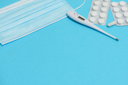 Scattered white pills on blue table.Medical, pharmacy and healthcare concept. Blue background white pills with a medical statoscope, top view.の写真素材