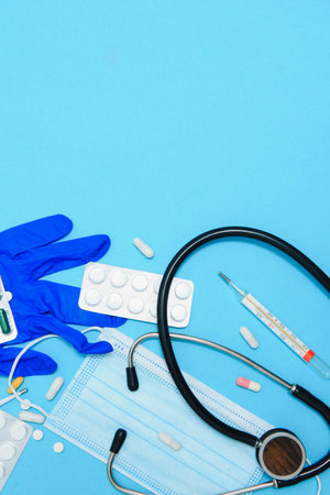 Scattered white pills on blue table.Medical, pharmacy and healthcare concept. Blue background white pills with a medical statoscope, top view.の写真素材