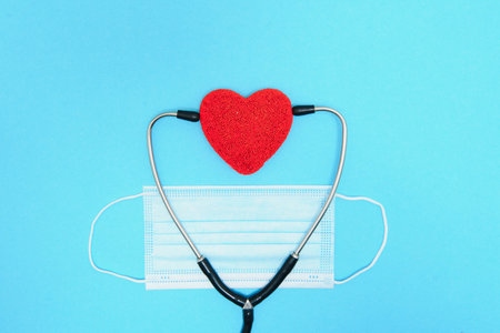 Global healthcare concept.Stylish doctor with heart on blue background.Close-up of red heart and stethoscope on a blue background. Listen to the heart with a statoscope.の写真素材