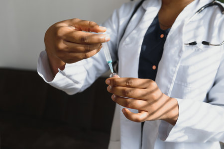 healthcare and medical concept - African doctor holding syringe with injectionの写真素材