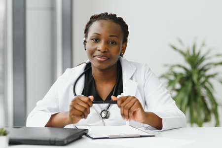 Closeup portrait of friendly, smiling confident female healthcare professional with lab coat, stethoscope, arms crossed. Isolated hospital clinic background. Time for an office visitの写真素材