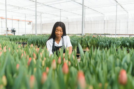 young african female nursery worker working inside greenhouse