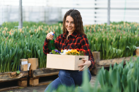 Beautiful young smiling girl, worker with flowers in greenhouse. Concept work in the greenhouse,...