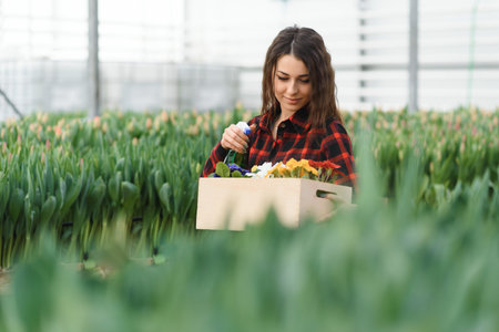 Beautiful young smiling Florists woman, worker with flowers in greenhouse. Concept work in the...