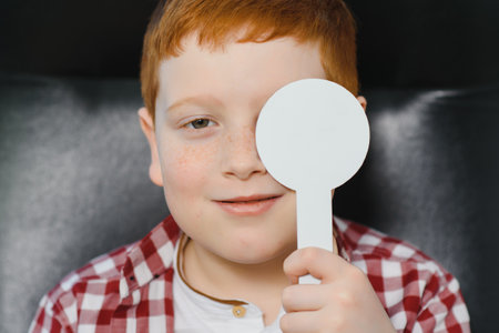 Child at eye sight test. Little kid selecting glasses at optician store. Eyesight measurement for...