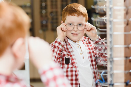 Handsome boy choosing glasses at optics store. health care and vision concept.の写真素材