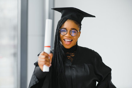 happy african american female student with diploma at graduationの写真素材