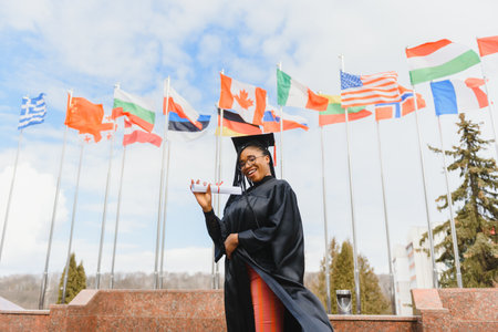 happy african american female student with diploma at graduationの写真素材