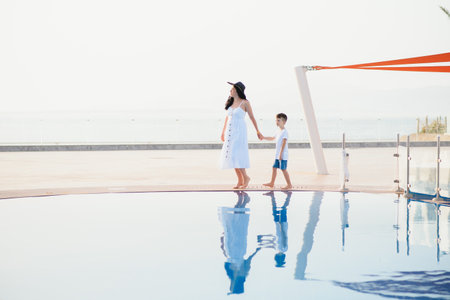Young mother and son walking near swimming pool. summer vacation conceptの写真素材