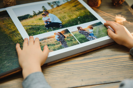 the Hand man holding a family photo album against the background of the a wooden table