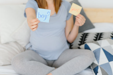 Pregnant woman with a sticky note and writing love boy or girl on sticky note and add on her belly,Pregnant Concept,Selective Focusの写真素材