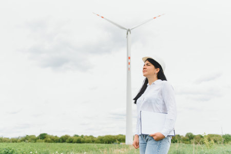women engineer working and holding the report at wind turbine farm Power Generator Station on...