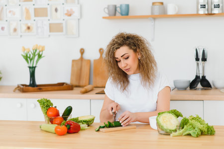 Happy young housewife mixing vegetable saladの写真素材