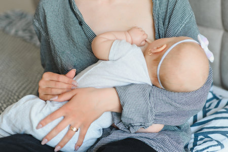 Soft photo young mother feeding breast her baby at home in white roomの写真素材