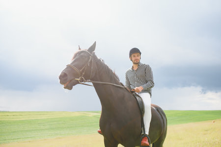 Beautiful man riding a horse on the field at summer.