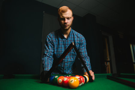 Young man playing billiards in the dark billiard club