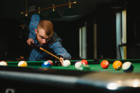 Young man playing billiards in the dark billiard clubの写真素材